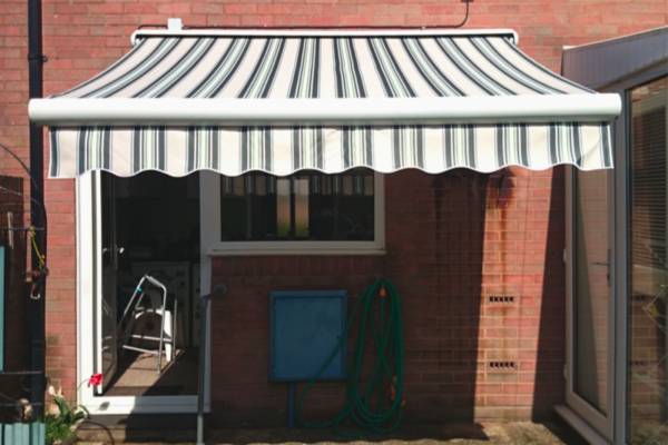 A photo of a garden awning above a back door of a house.