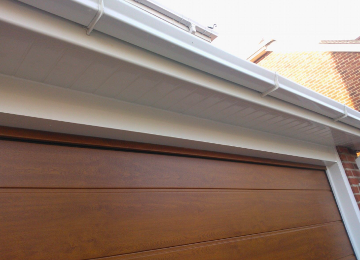 A wooden sectional garage door and guttering above.