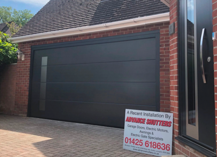 A newly fitted, black, sectional garage door and front door on a house in Christchurch.