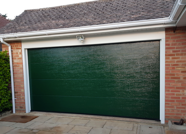 A dark green sectional garage door fitted to a property in Hampshire.